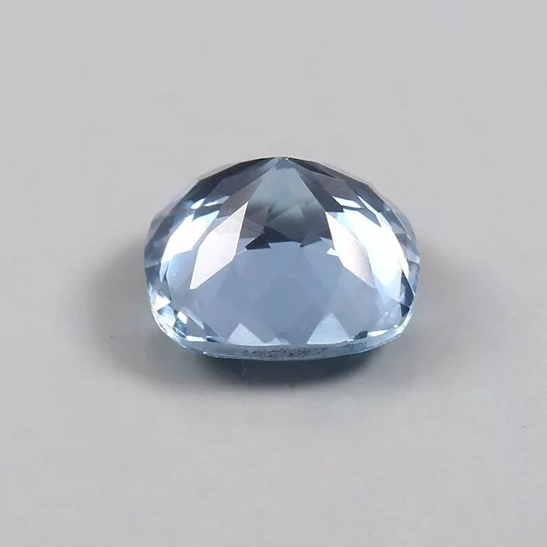 Faceted blue Aquamarine gemstone on a gray background