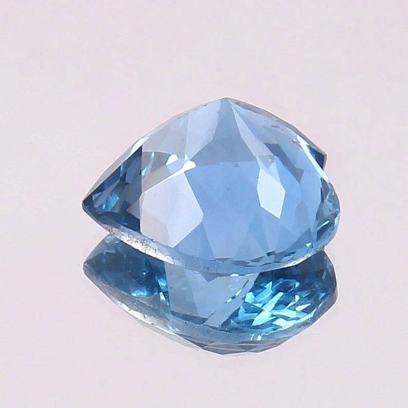 Faceted blue Aquamarine gemstone on a light pink background