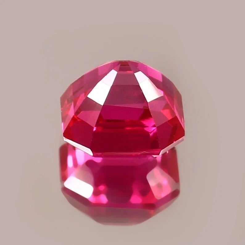 Faceted red gemstone on a beige background