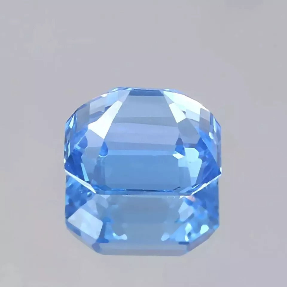 Faceted blue Spinel gemstone on a gray background
