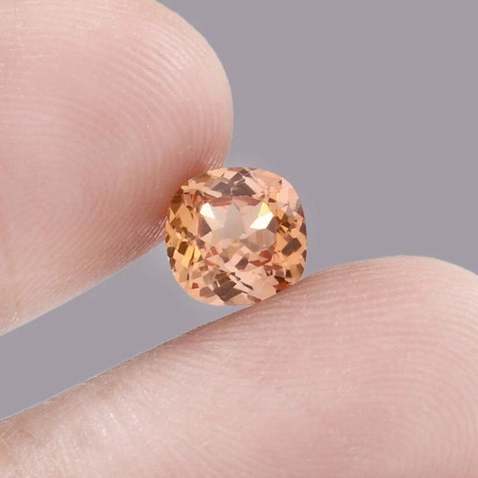 Padparadscha Sapphire – Peach to Orange gemstone held between two fingers against a neutral background