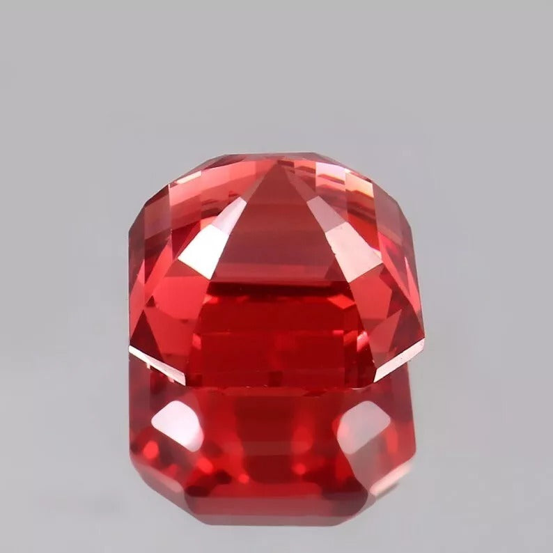 Faceted Solomon Padparadscha Sapphire gemstone on a gray background