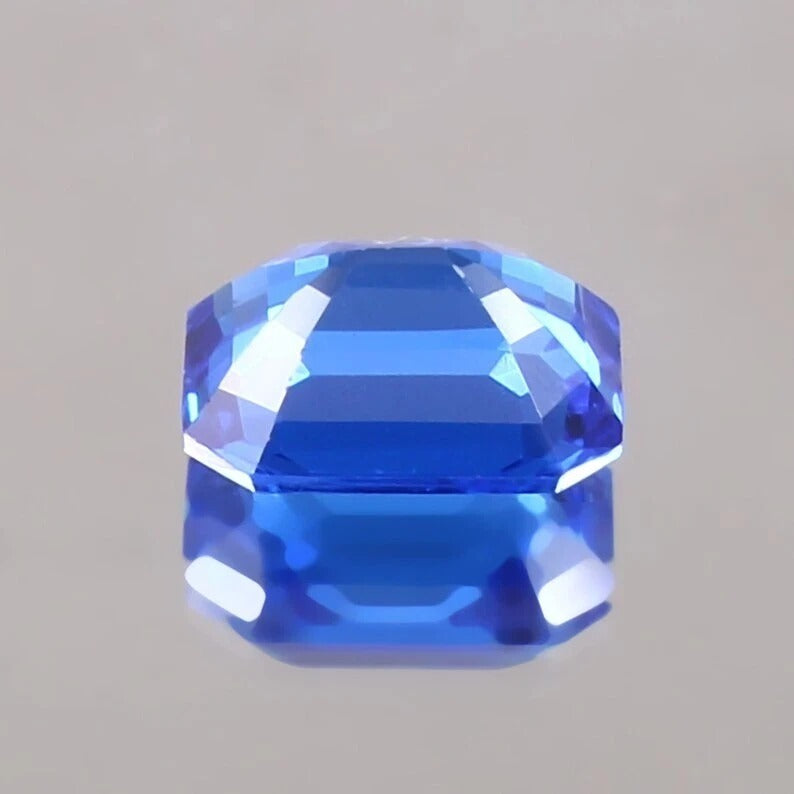Faceted Cornflower Blue Sapphire gemstone on a gray background