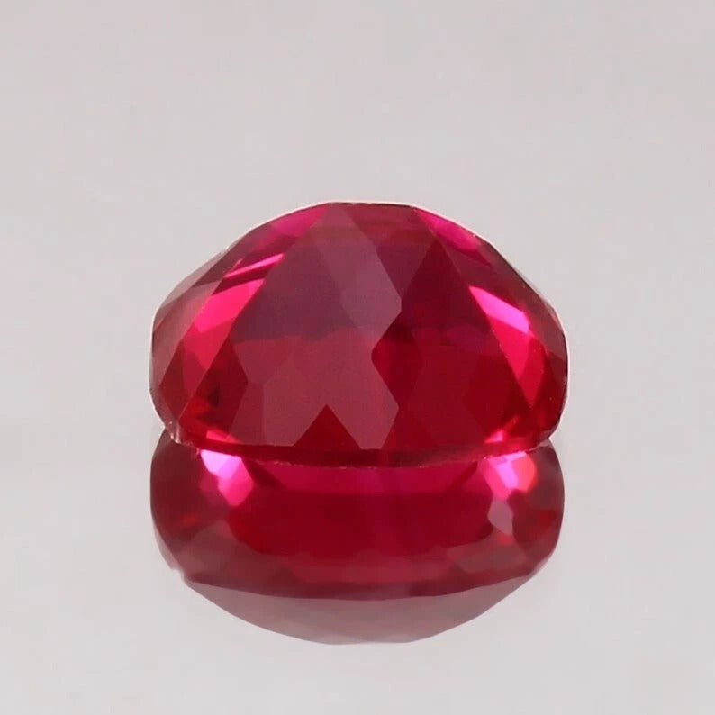 Faceted Pigeon Blood Ruby gemstone on a light gray background