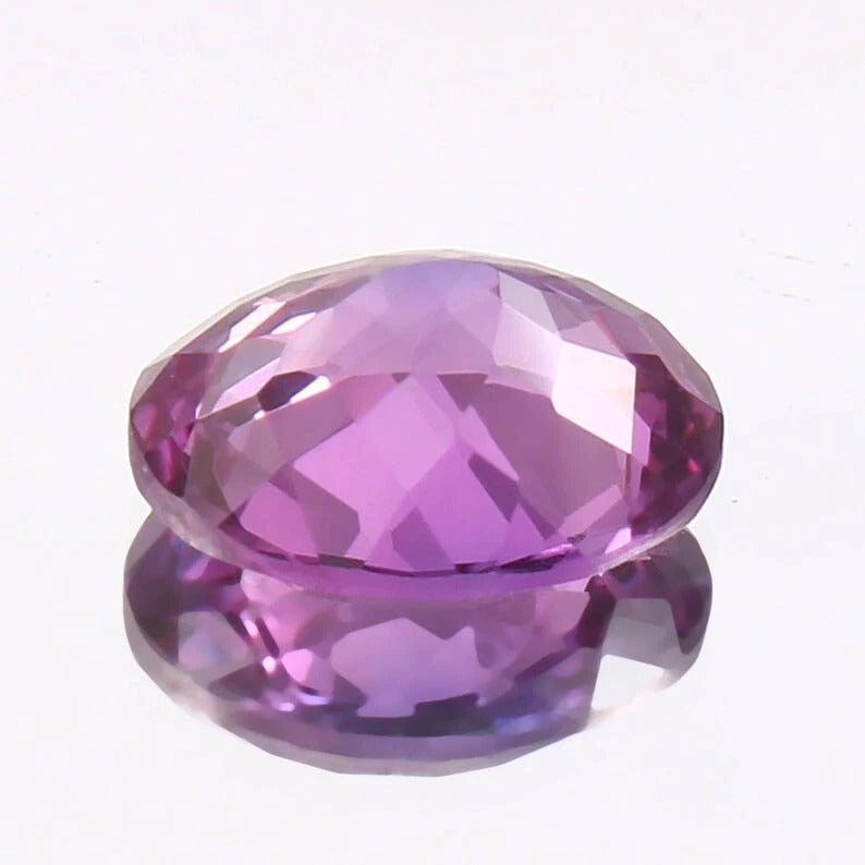 Faceted Taaffeite purple gemstone on a white background
