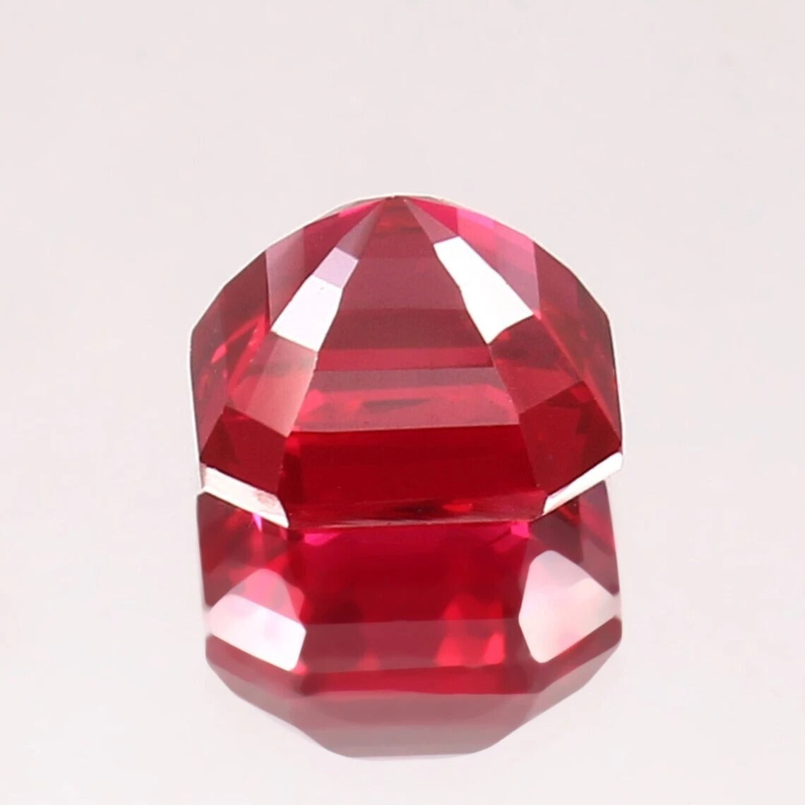 Faceted red ruby Mogok gemstone on a light gray background
