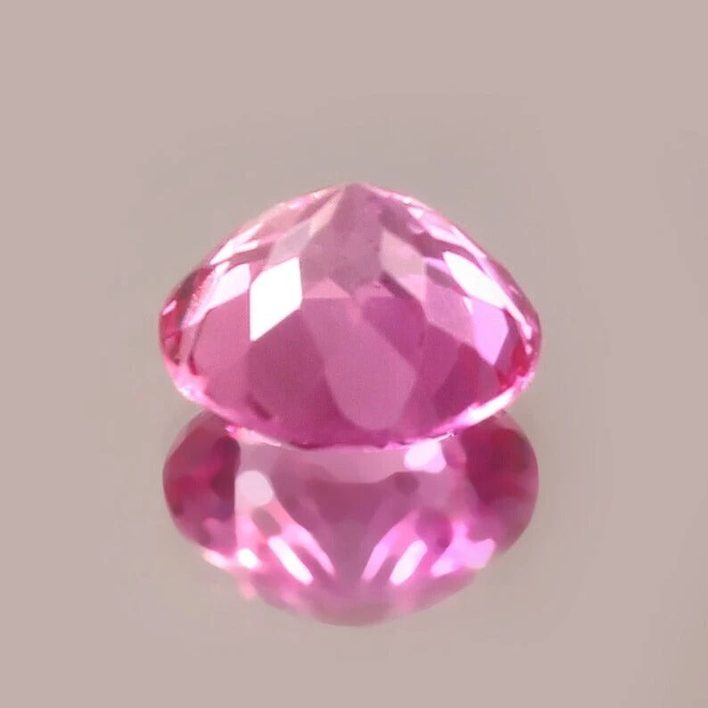 Faceted pink sapphire gemstone on a light gray background
