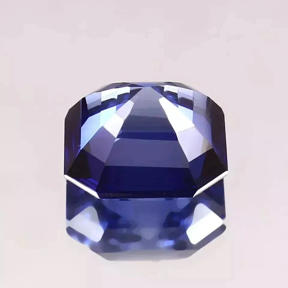 Faceted Royal Blue Sapphire gemstone on a light gray background