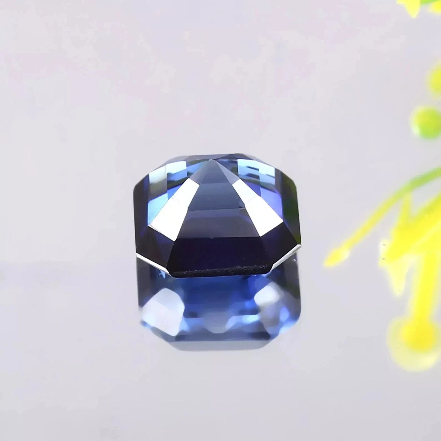 Faceted Blue Sapphire gemstone on a light gray background