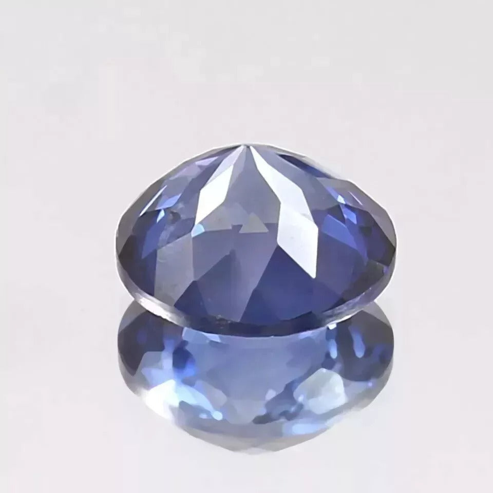 Faceted Royal Blue Sapphire Round Cut gemstone on a light gray background