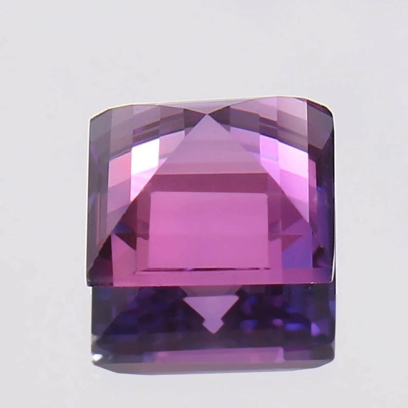 Square-cut Purple Pink Ceylon Sapphire gemstone on a light gray background