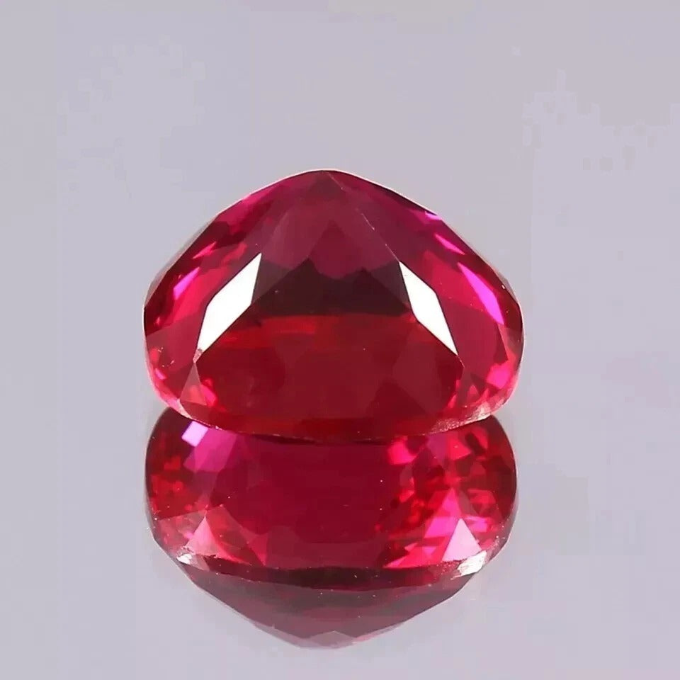 Faceted red Mozambique Ruby gemstone on a light gray background