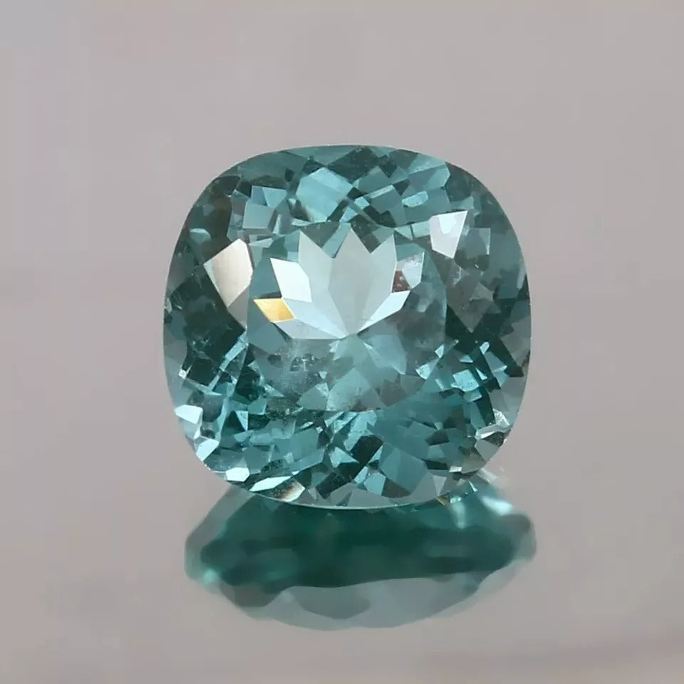 Teal Spinel gemstone on a gray background
