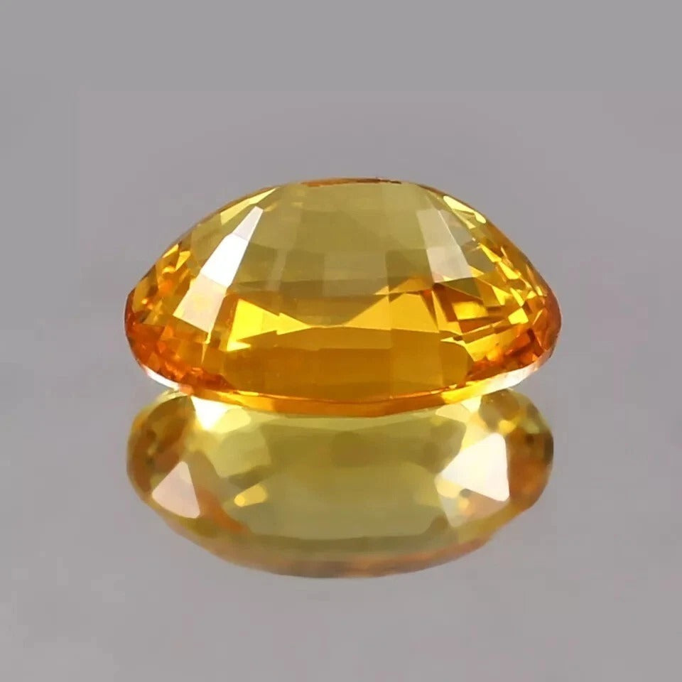 Yellow Sapphire gemstone on a reflective gray surface
