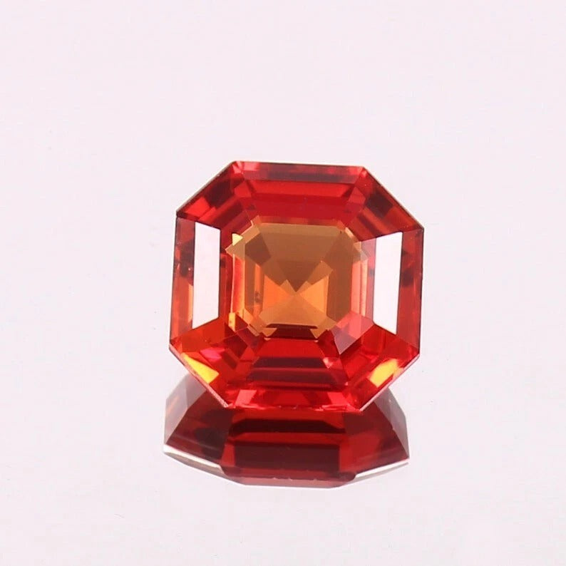 Faceted orange sapphire gemstone on a white background
