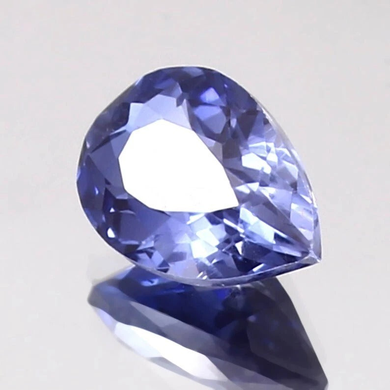 Faceted blue Kashmir Sapphire gemstone on a light gray background