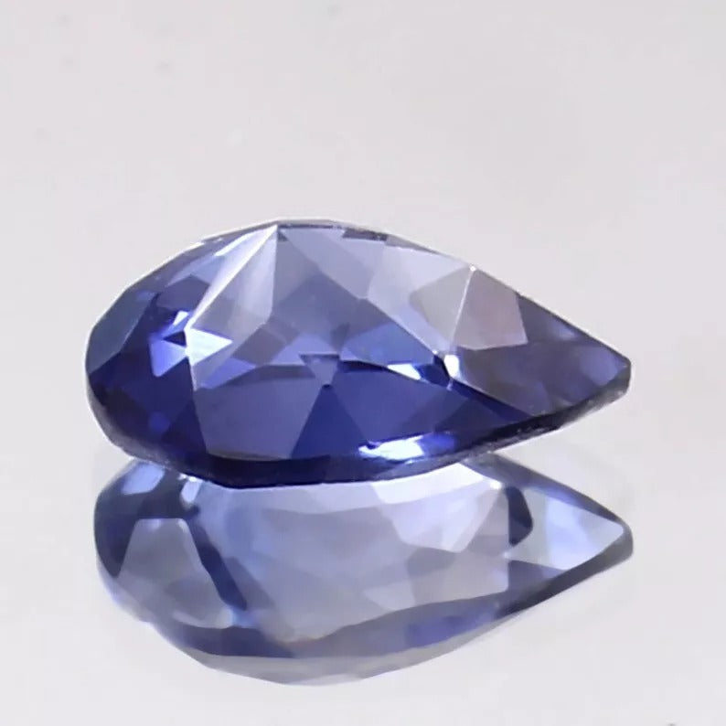 Faceted blue Kashmir Sapphire gemstone on a light gray background