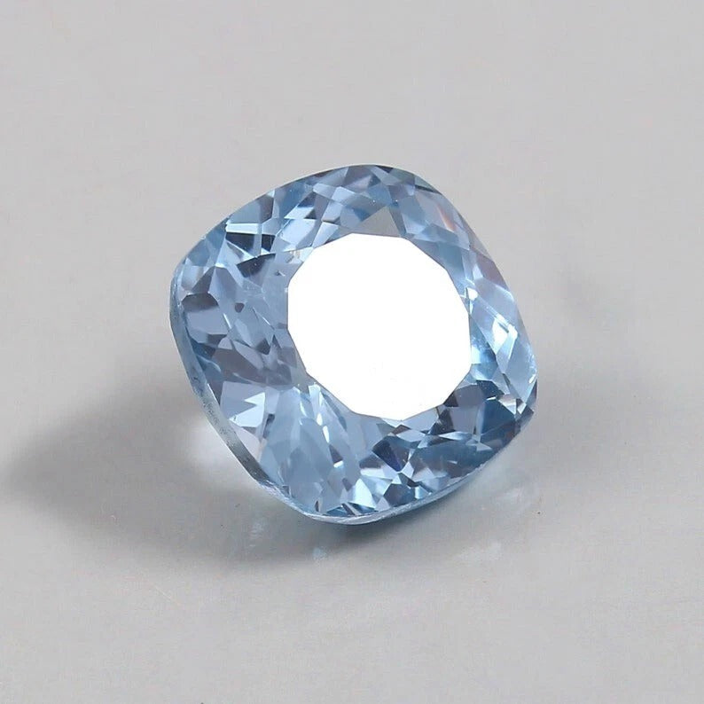 Clear blue Aquamarine gemstone on a light gray background