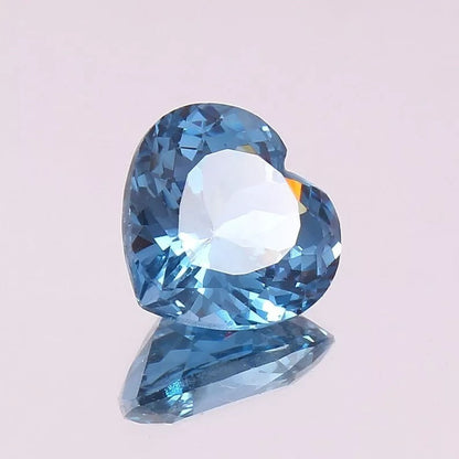 Heart-shaped blue Aquamarine gemstone on a light pink background
