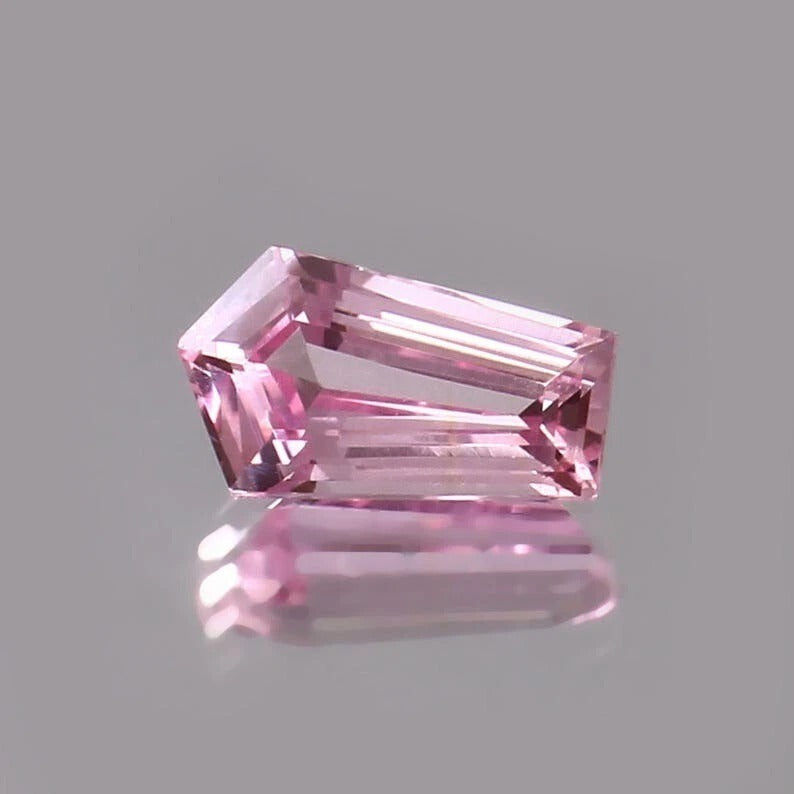 Pink Padparadscha Sapphire gemstone on a gray background