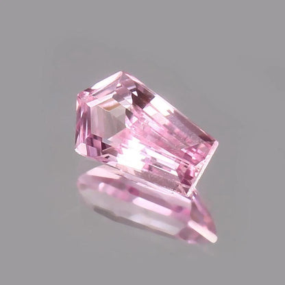 Pink Padparadscha Sapphire gemstone on a gray background