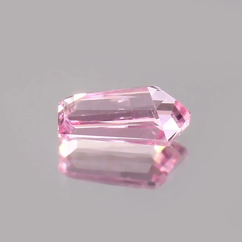 Pink Padparadscha Sapphire gemstone on a gray background
