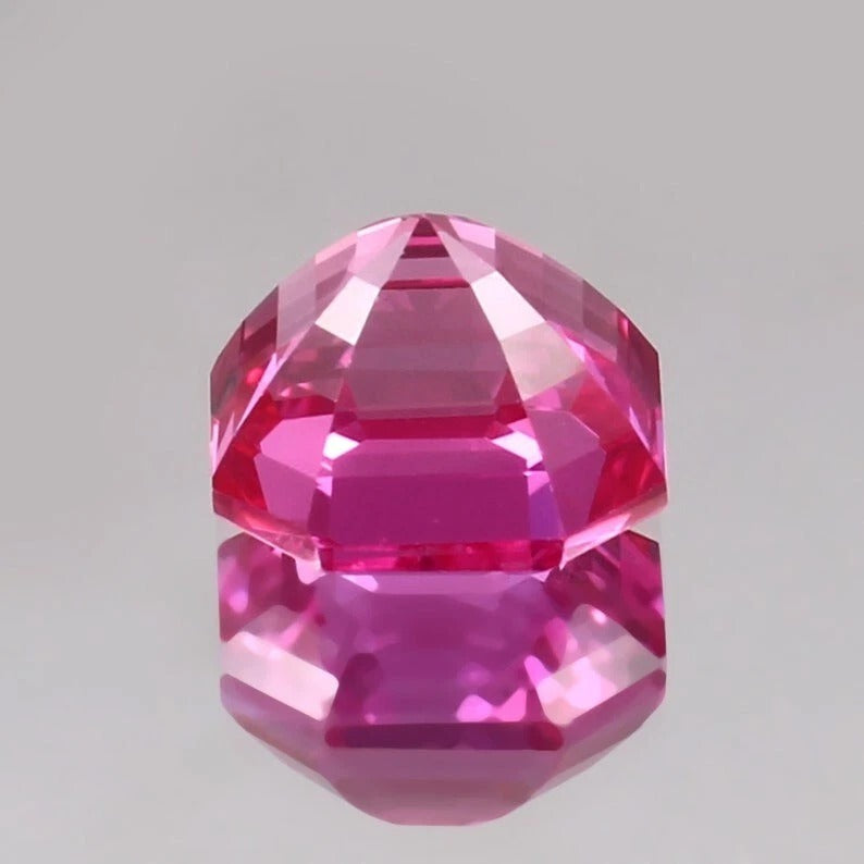 Faceted pink  sapphire asscher gemstone on a gray background