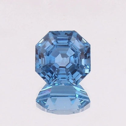 Swiss Blue Topaz gemstone with a faceted cut on a light gray background