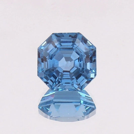 Swiss Blue Topaz gemstone with a faceted cut on a light gray background