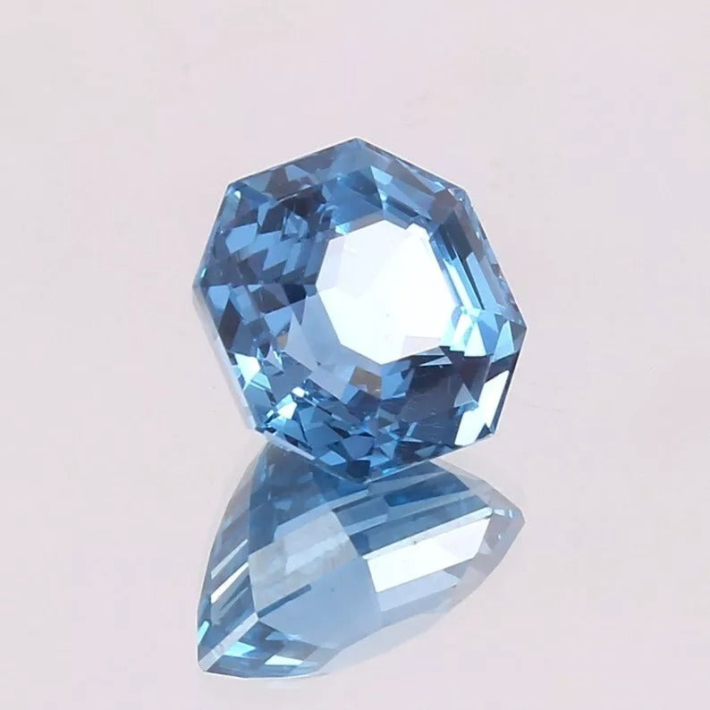 Faceted Swiss Blue Topaz gemstone on a light gray background