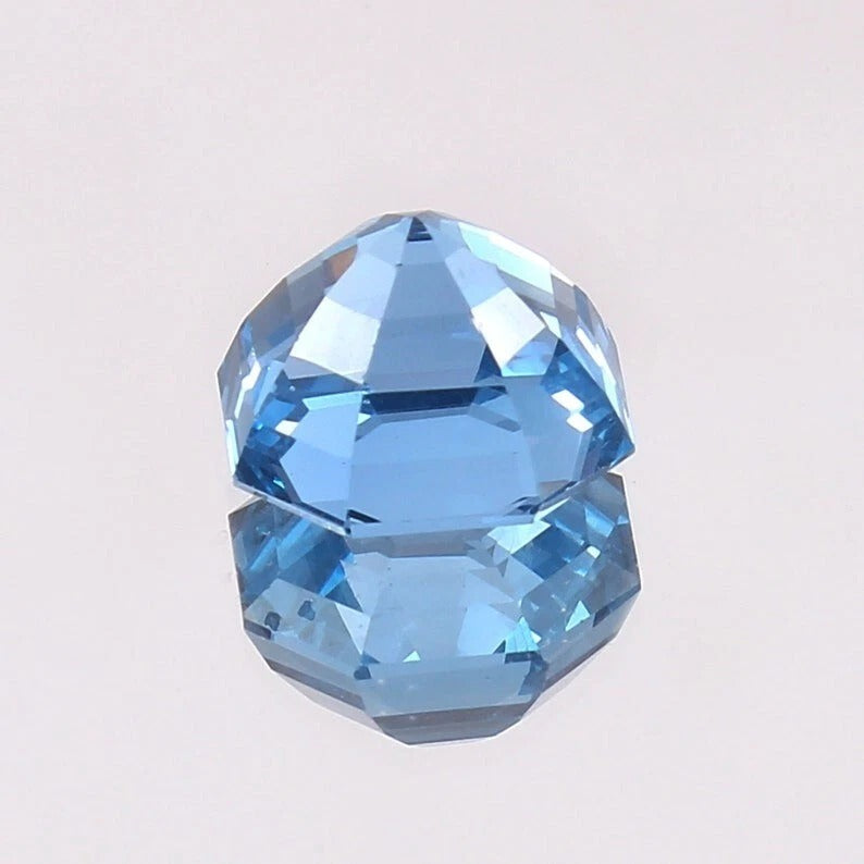 Faceted Swiss Blue Topaz gemstone on a light gray background