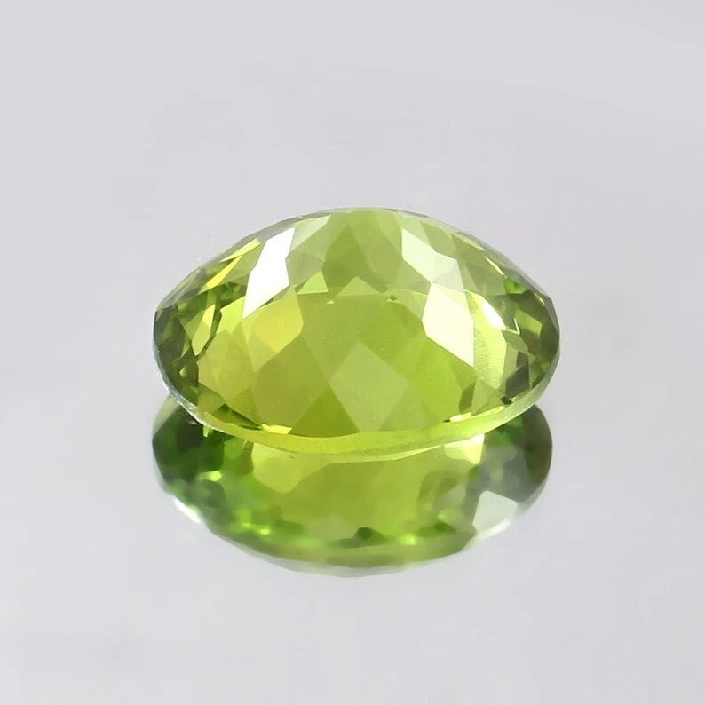 Faceted green Peridot gemstone on a light gray background