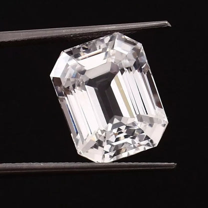 emerald cut White Sapphire held by tweezers against a black background