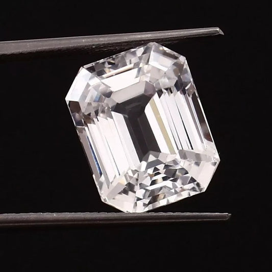 emerald cut White Sapphire held by tweezers against a black background