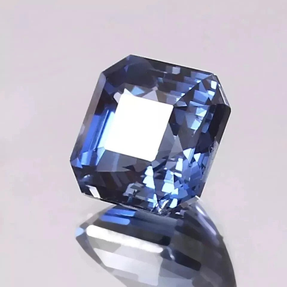 Blue sapphire on a reflective surface with a light gray background