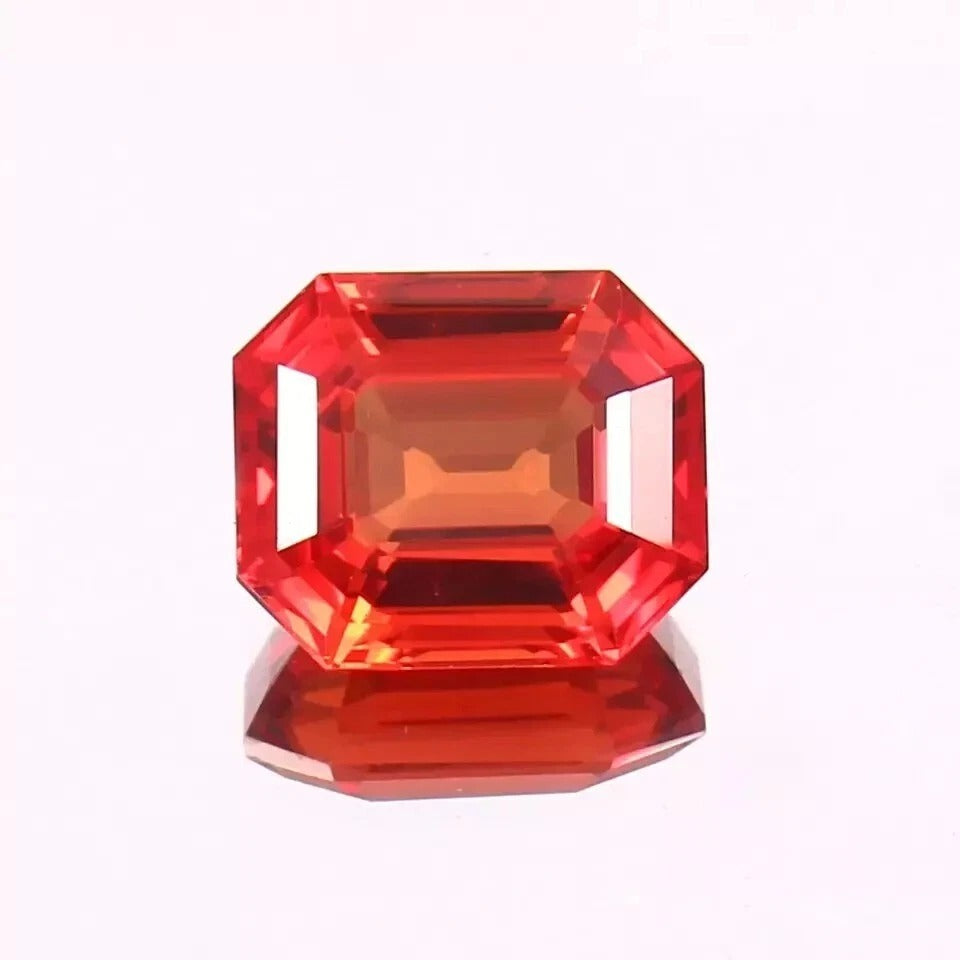 Fanta Orange Sapphire gemstone with a faceted cut on a white background