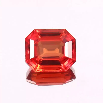 Fanta Orange Sapphire gemstone with a faceted cut on a white background