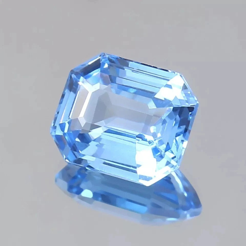 Blue Spinel gemstone with a hexagonal cut on a gray background