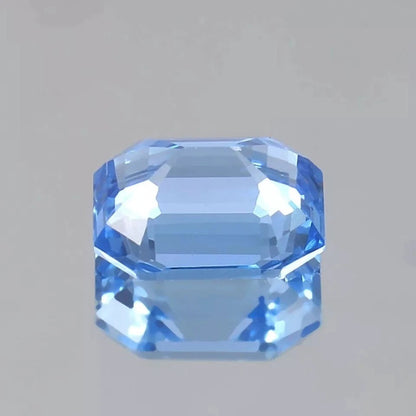 Faceted blue Spinel gemstone on a gray background