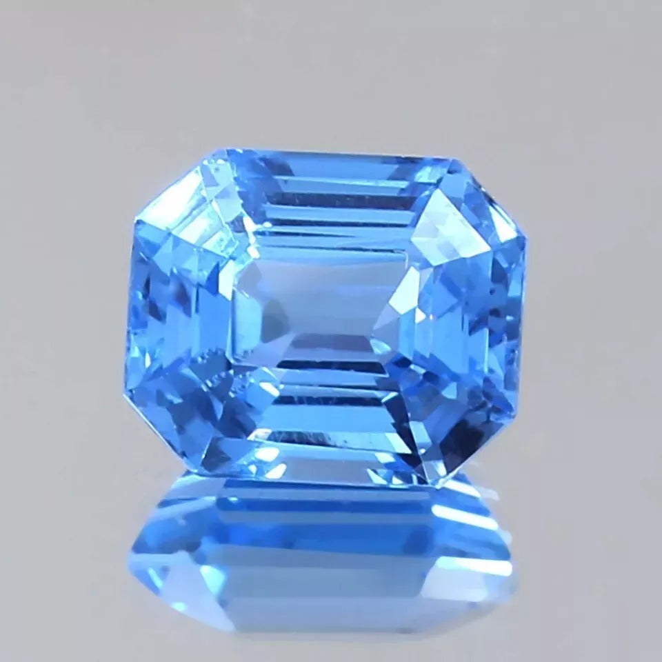 Faceted blue Spinel gemstone on a gray background