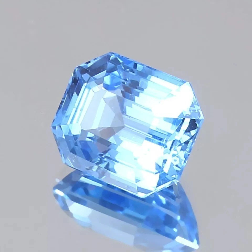 Faceted blue Spinel gemstone on a gray background