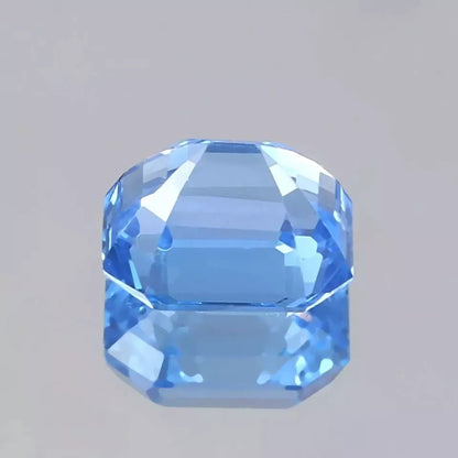 Faceted blue Spinel gemstone on a gray background
