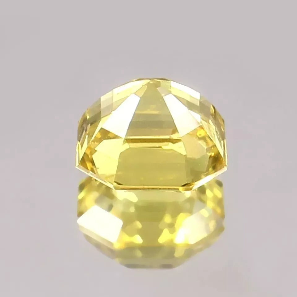 Faceted yellow Sapphire gemstone on a gray background