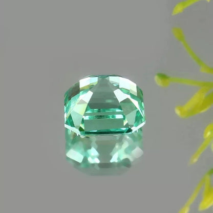 Green Sapphire gemstone on a gray background with a yellow flower