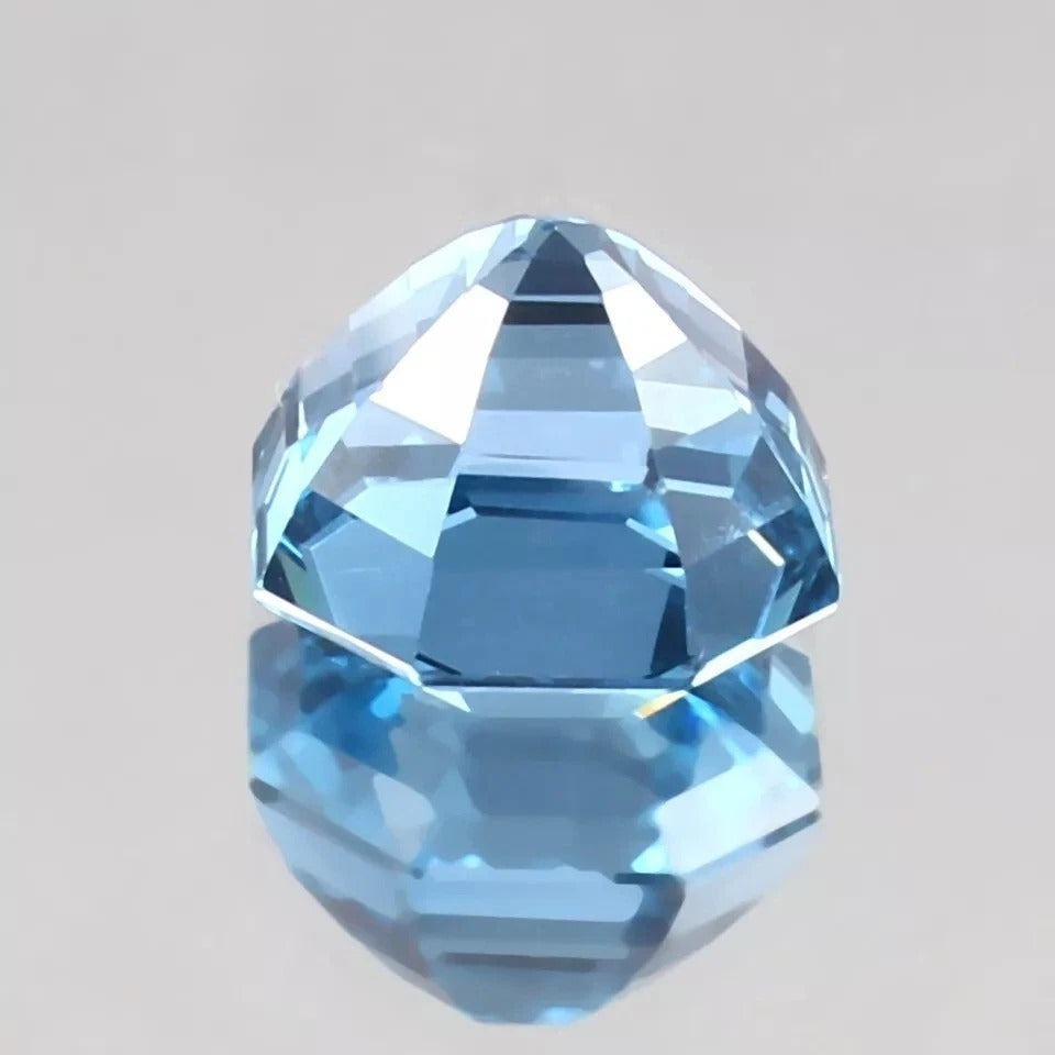 Faceted blue Brazilian Aquamarine gemstone on a gray background