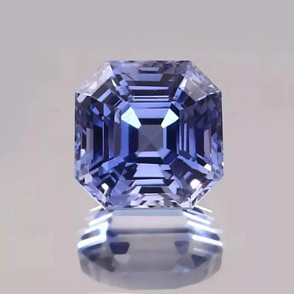 Asscher-cut Blue sapphire gemstone on a reflective surface with a gray background