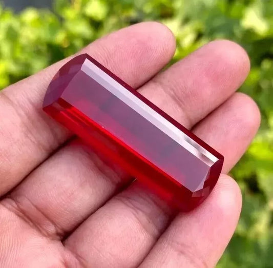 Red huge burma Ruby held in a hand with a blurred green background