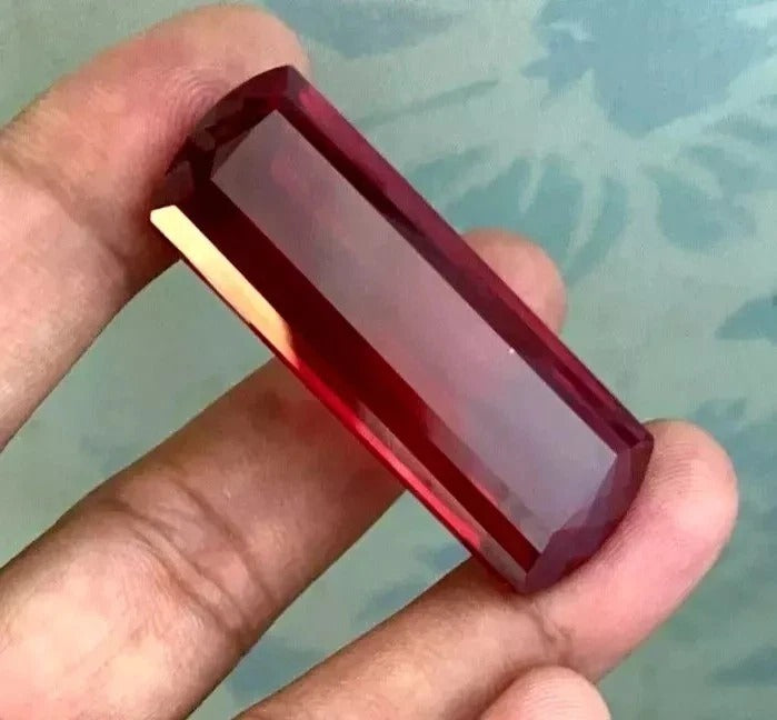 Hand holding a Red huge burma Ruby against a blurred background