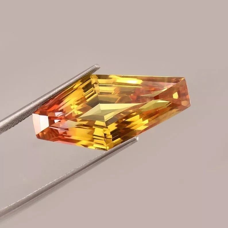 Faceted Bi-Color Sapphire gemstone held by tweezers on a neutral background