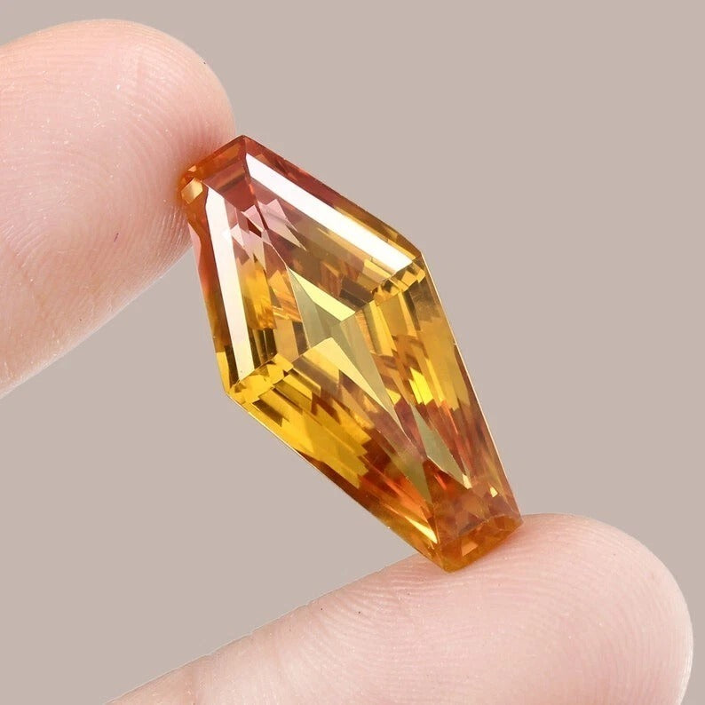 Faceted Bi-Color Sapphire gemstone held between fingers against a neutral background